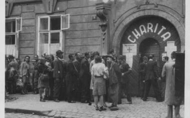 Zástup před sídlem Ústředí svazů katolické Charity v Pětikostelní (Sněmovní) 9 v Praze. Péče o navrátilce pod ochranou Mezinárodního Červeného kříže