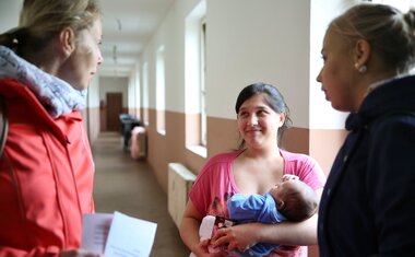 Sociální pracovnice hovoří s mladou maminkou na ubytovně